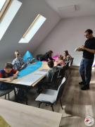 Grupa dzieci przy stole klei niebieski model balonu