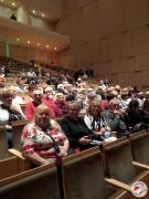 Seniorzy siedzą na sali w oczekiwaniu na koncert