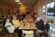Zebrani członkowie Klubu Seniora piją kawę i herbatę 