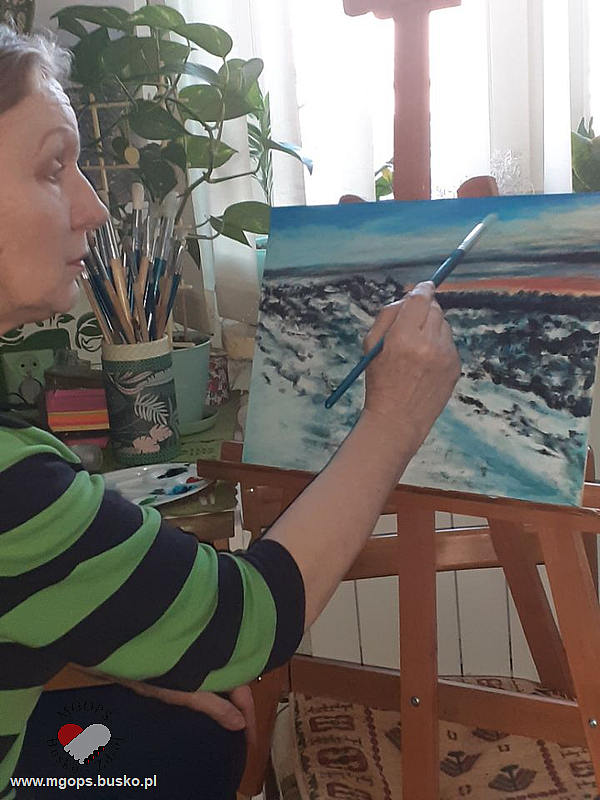 Seniorka maluje pejzaż przedstawiający wzburzone morze
